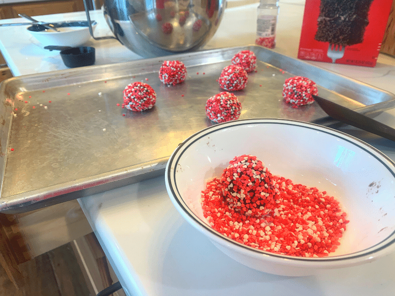 coating chocolate valentine's cookies in sprinkles