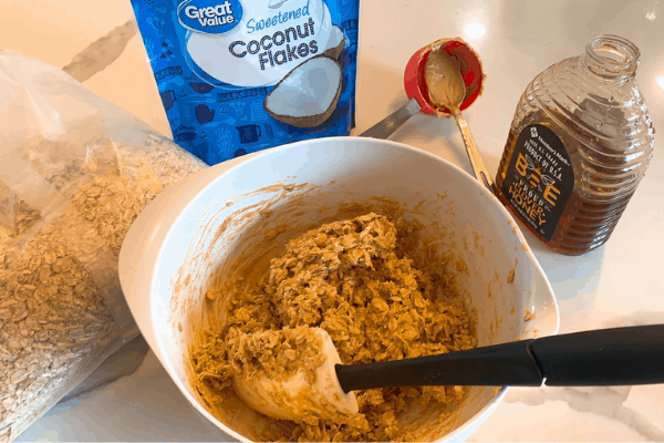 picture of energy ball batter in a white bowl surrounded by ingredients
