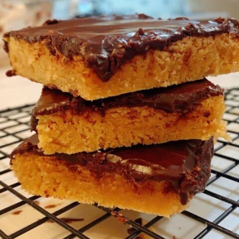 3 peanut butter brownies with chocolate frosting stacked on cooling rack